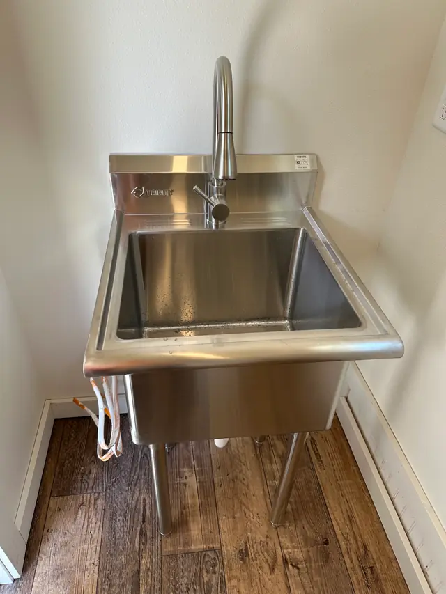 A stainless utility sink with a pull-down faucet installed by CSR Plumbing