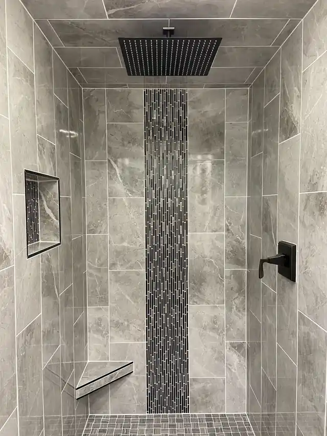 A finished tiled shower with a matte-black rain head and valve trim installed by CSR Plumbing