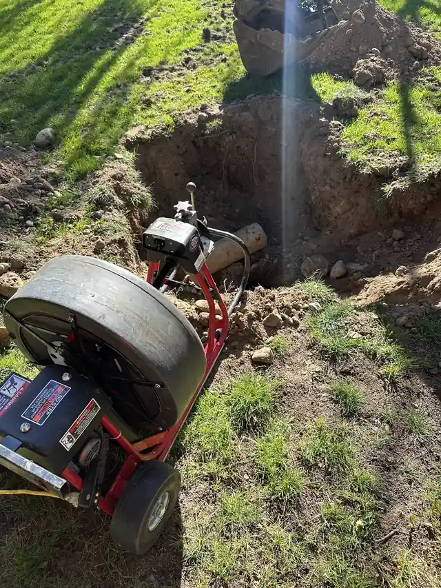 CSR's drum drain machine working at an excavated sewer pit in a lawn