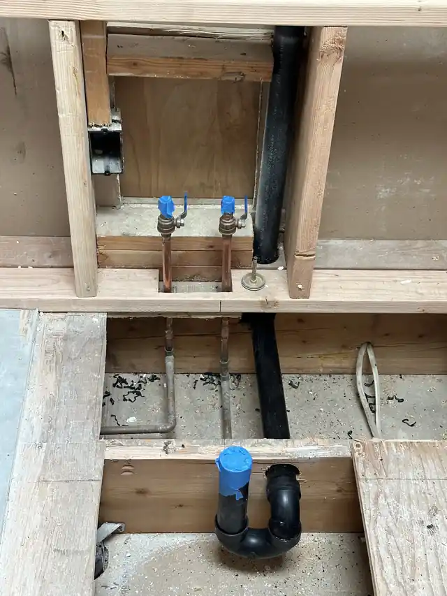 New drain and supply rough-in with a blue test cap, ready for testing before the floor closes
