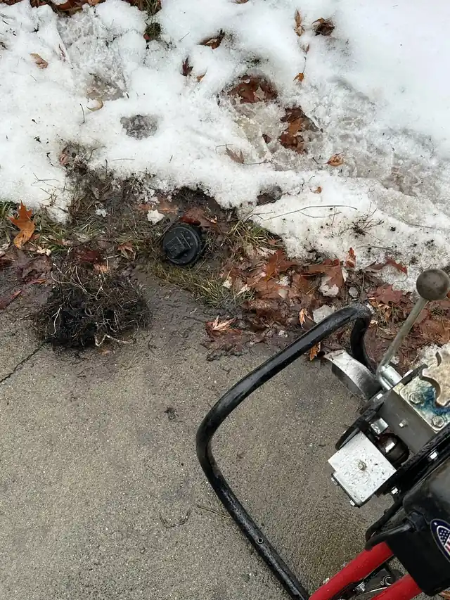 CSR's drain machine at an outdoor sewer cleanout on a snowy winter call